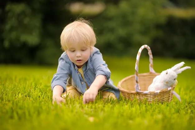 Charming little boy hunting for easter egg in spring park on easter day. Premium Photo