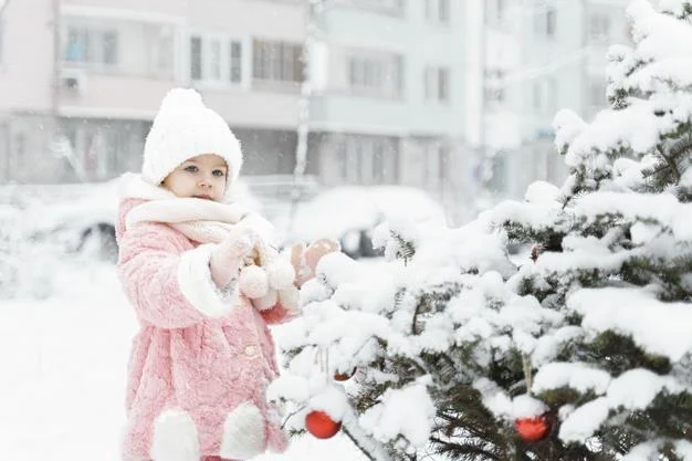 Little girl decorates a christmas tree in the yard. Premium Photo