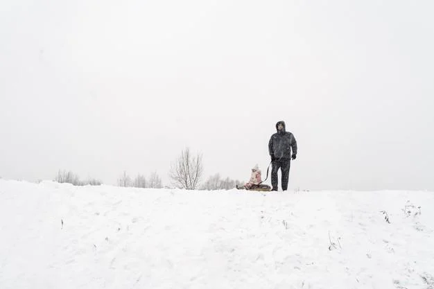 Dad and daughter on a snow slide with tubing in a blizzard Premium Photo